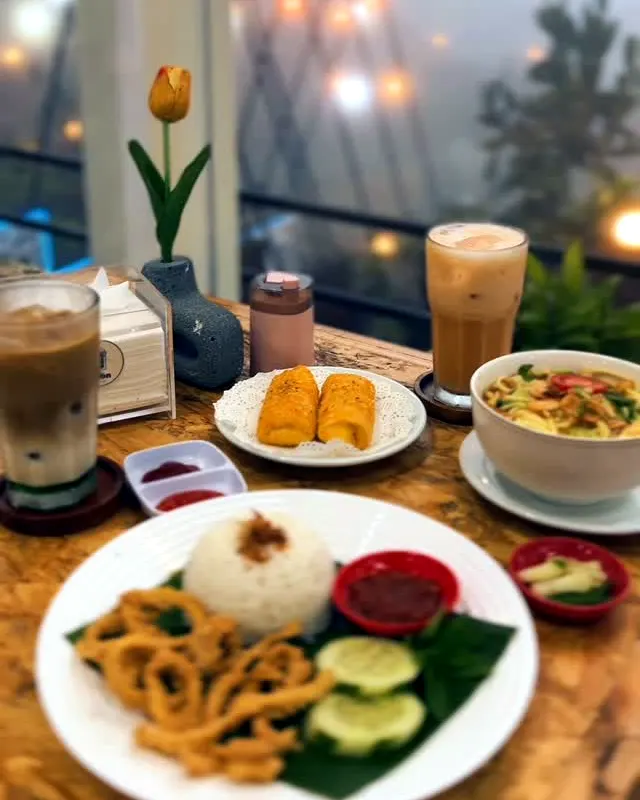Nasi dengan cumi krispi, risol, sup, dan kopi di meja kayu dekat jendela berkabut berhias bunga tulip
